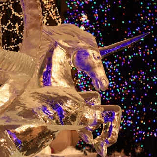 close-up of a gold unicorn statue at Saint Paul Winter Carnival. colorful holiday lights are in the background